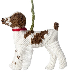 May include: A white and brown knitted dog ornament with a red collar and a green string for hanging.