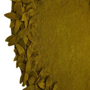 May include: A round, olive green felt rug with a border of 3D felt leaves. The leaves are arranged in a circular pattern around the edge of the rug.