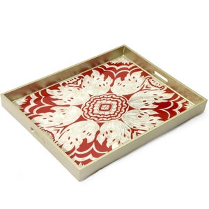 May include: Rectangular serving tray with a red and cream floral design. The tray has a gold-colored frame and integrated handles. The floral pattern is centered on the tray's surface.