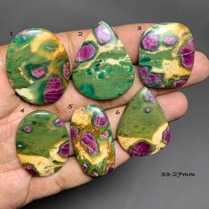 Puede incluir: Seis piedras preciosas cabujón pulidas con una mezcla de inclusiones verdes, crema y rosa magenta. Las piedras están numeradas del uno al seis, con formas ovaladas y de lágrima. El texto 33-27mm es visible en la esquina inferior derecha.