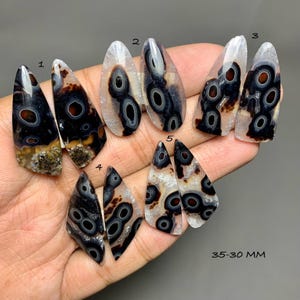 May include: Ten teardrop-shaped cabochons of orbicular agate, arranged in five pairs labelled 1 through 5. Each stone features concentric black and brown rings on a translucent white base. The text 35-30 MM is visible in the bottom right corner.
