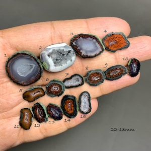 May include: A collection of polished agate geodes in various shapes and colors, including shades of gray, brown, and orange. The geodes range in size from approximately 0.5 to 1 inch. The text "22-13mm" is visible. These natural stones are ideal for collectors or jewelry making.