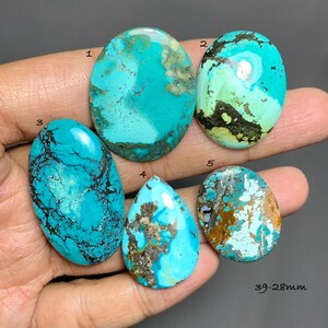 Puede incluir: Cinco cabujones de turquesa pulidos numerados del 1 al 5, que muestran varios tonos de azul y verde con patrones de matriz marrón oscuro. Las piedras tienen forma ovalada y de lágrima, con un tamaño indicado de 39-28mm en la imagen.