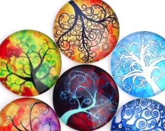 Könnte beinhalten: Zwölf runde Glascabochons mit bunten Baumdesigns. Jeder Cabochon zeigt ein anderes Baumdesign mit wirbelnden Ästen und Blättern in verschiedenen Farben, darunter Blau, Grün, Rot, Lila und Gelb.