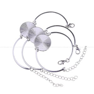 Puede incluir: Tres pulseras de tono plateado con engastes circulares que presentan una textura radial similar a rayos de sol. Cada pulsera incluye una banda metálica curva, un cierre de mosquetón y una cadena de extensión ajustable.