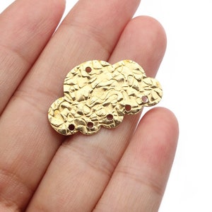 Könnte beinhalten: Goldfarbener Metall-Wolkenanhänger mit strukturierter Oberfläche und fünf Löchern. Der Anhänger ist für die Schmuckherstellung oder andere Bastelprojekte gedacht.