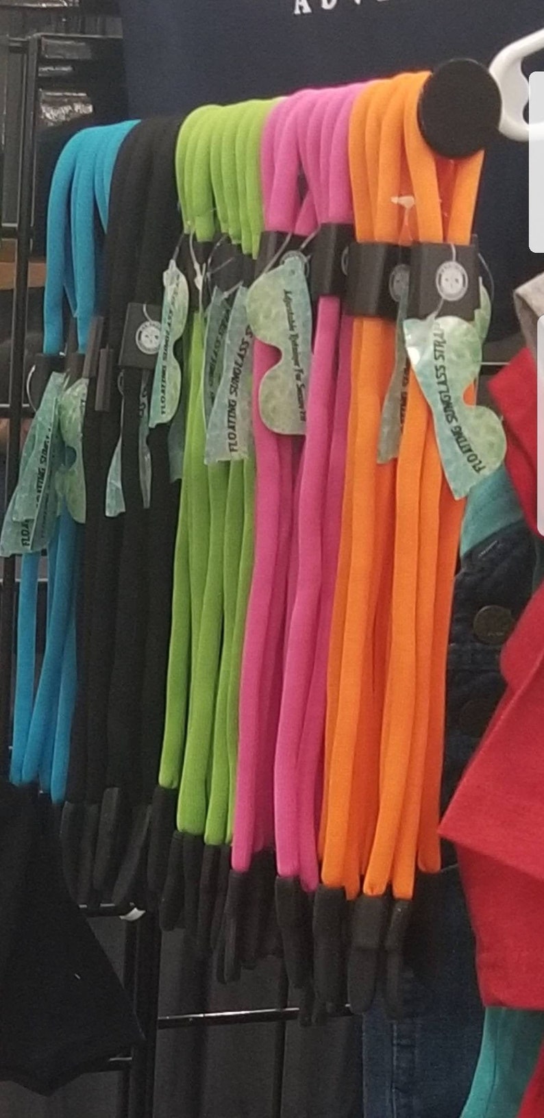May include: Assortment of colorful floating sunglass straps. The straps are made of a soft, flexible material and are available in a variety of colors, including blue, green, pink, and orange. The straps are labeled "Floating Sunglass Straps" and "Adjustable Retainer For Seniors 18".