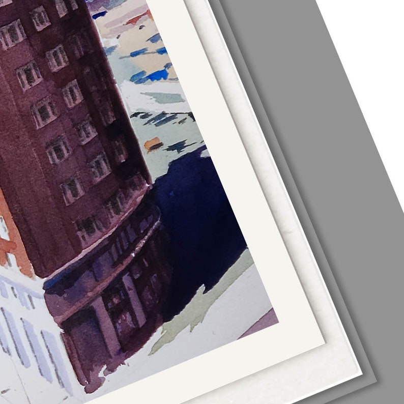 May include: A watercolor painting of a city scene with a tall building in the foreground. The building is painted in shades of brown and gray, with a white trim. The building is surrounded by other buildings, which are painted in shades of blue and gray. The painting is framed in a white mat.