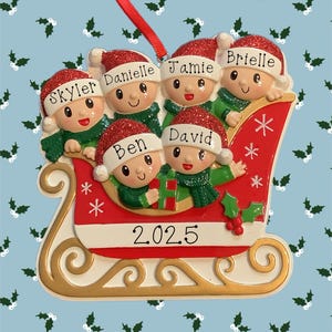 May include: A Christmas ornament featuring a family of five in a red and white sleigh. Each figure wears a red Santa hat with a name on it: Skyler, Danielle, Jamie, Brielle, Ben, and David. The year 2025 is displayed on the sleigh.