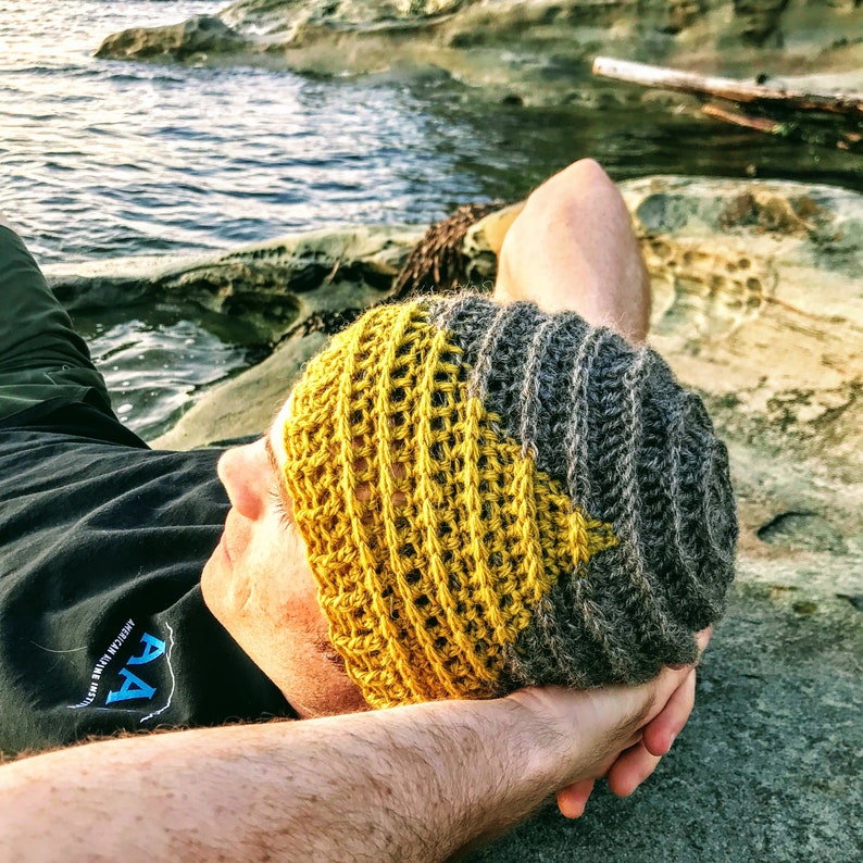 Puede incluir: Una persona lleva una boina de crochet amarilla y gris. La boina tiene un dise&ntilde;o texturizado y est&aacute; hecha de hilo.