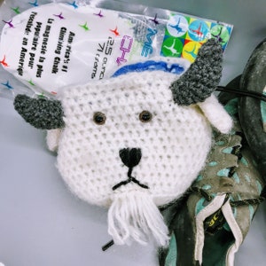 Può includere: Testa di capra in crochet bianco con occhi, naso e corna neri. La testa di capra è seduta su una scarpa blu e verde.