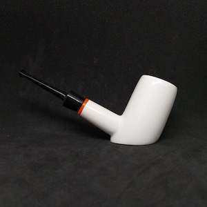 May include: A white ceramic pipe with a black and orange stem.