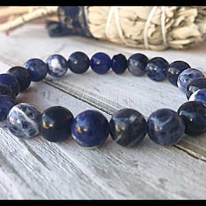 May include: A blue and white beaded bracelet made of natural stones. The bracelet is made of round beads and is elastic.