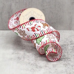 May include: A roll of Christmas ribbon with a white base and festive designs. The ribbon displays candy canes, gingerbread men, and snowflakes, with red and green striped accents. The edges are trimmed in red.