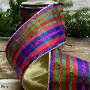 Op de afbeelding: Een levendig geruit lint in roze, rood, groen en blauw met gouden rand. Het lint heeft glitteraccenten en is op een spoel gerold. Het woord "Pink" is onderaan zichtbaar.