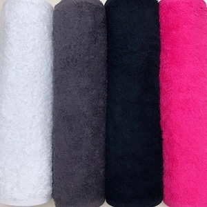 May include: Four rolled up towels in different colors: white, gray, black, and pink.