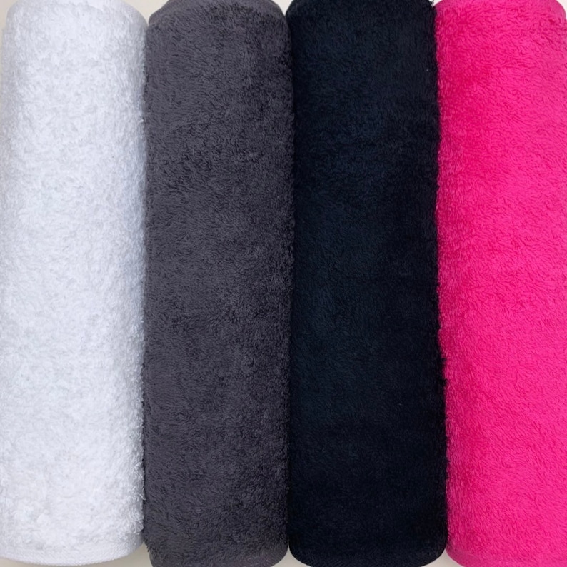 May include: Four rolled up towels in different colors: white, gray, black, and pink.