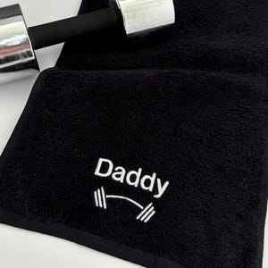 May include: Black gym towel with white embroidery that says "Daddy" with a dumbbell graphic.