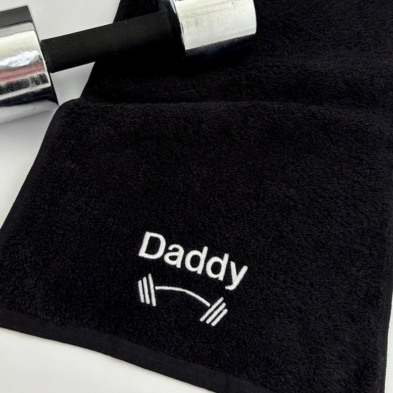May include: Black gym towel with white embroidery that says "Daddy" with a dumbbell graphic.