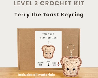 May include: A crochet kit for a Terry the Toast keyring. The kit includes all materials and is level 2. The image shows a finished keyring next to the kit box. The keyring is a slice of toast with a smiling face and a keychain ring. The box has the text "Terry the Toast Keyring".