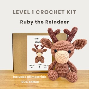Könnte beinhalten: Ein Häkelset für Ruby das Rentier, ein braunes und beiges Amigurumi-Reh. Das Set enthält alle Materialien und ist Level 1. Der Text auf der Box lautet "LEVEL 1 CROCHET KIT Ruby the Reindeer" und "Includes all materials 100% cotton."