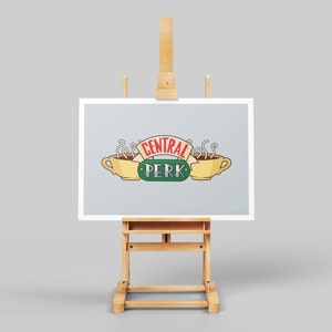 May include: A framed print on an easel with the text "Central Perk" and two coffee cups with steam coming from them.