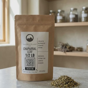 May include: A brown paper pouch labelled Sacred Plant Co Chaparral Leaf 1/2 LB with a QR code and text including Low Water Regenerative Colorado Farming, Herb Notes, External Only, Aromatic, Cleansing, and Lot #CHPLA, with dried herbs beside it.