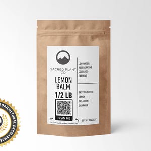 A resealable kraft paper bag Sacred Plant Co Lemon Balm 1/2 LB, tasting notes of lemon, spearmint, and camphor. A circular cutout reveals the vibrant green and finely chopped lemon balm leaves. Recognized for innovative agricultural excellence.