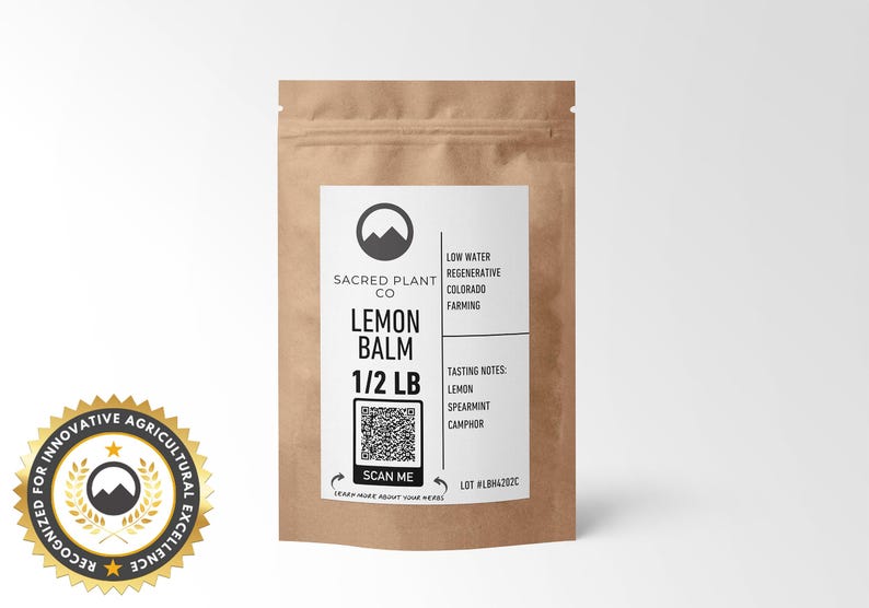 A resealable kraft paper bag Sacred Plant Co Lemon Balm 1/2 LB, tasting notes of lemon, spearmint, and camphor. A circular cutout reveals the vibrant green and finely chopped lemon balm leaves. Recognized for innovative agricultural excellence.