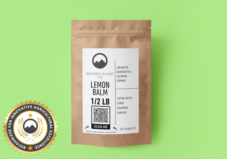A resealable kraft paper bag Sacred Plant Co Lemon Balm 1/2 LB, tasting notes of lemon, spearmint, and camphor. A circular cutout reveals the vibrant green and finely chopped lemon balm leaves. Recognized for innovative agricultural excellence.