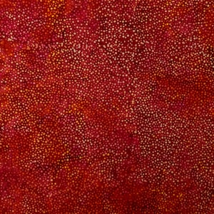 Könnte beinhalten: Roter Stoff mit einem verstreuten Muster aus kleinen weißen und orangefarbenen Punkten.