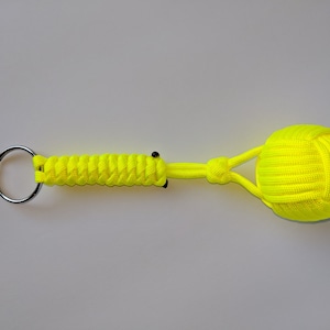 May include: A bright yellow paracord keychain with a knotted ball at the end. The keychain has a silver metal ring.
