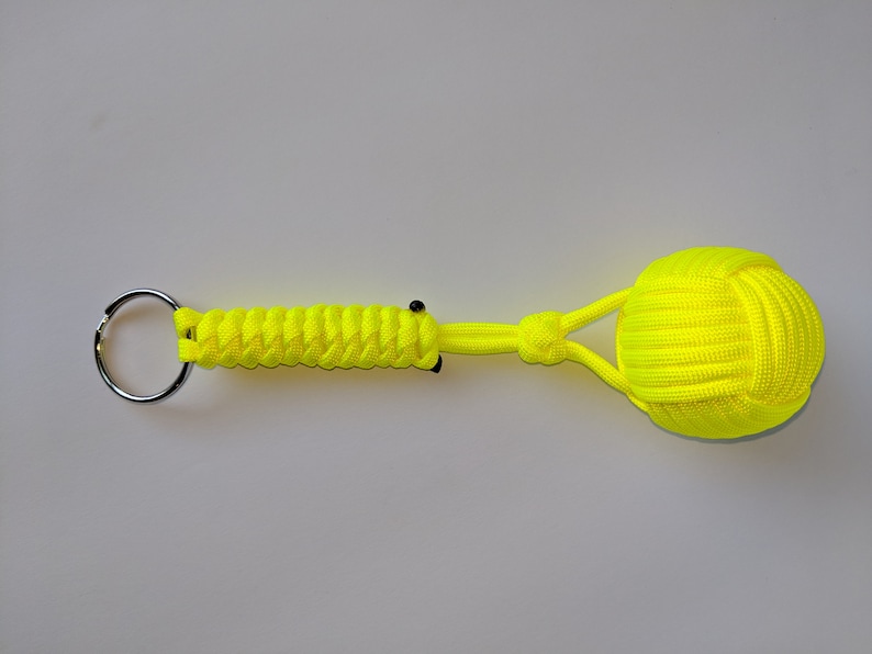 May include: A bright yellow paracord keychain with a knotted ball at the end. The keychain has a silver metal ring.