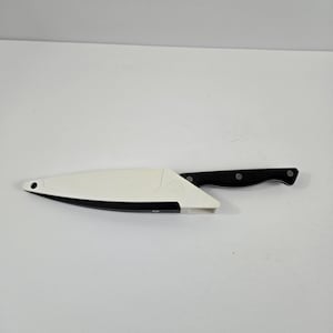 May include: A black and silver kitchen knife with a black handle and a white blade cover. The knife is designed for cutting and slicing food. The blade cover is white with a black trim.