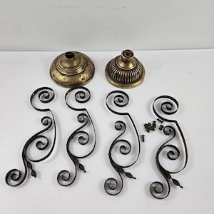May include: An antique brass and black metal chandelier parts set. The set includes two brass bases, four black metal decorative scrollwork pieces, and small screws. The parts are arranged on a white surface.