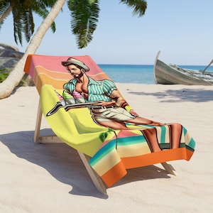 Puede incluir: Una toalla de playa con un diseño retro que presenta a un hombre con una camisa a rayas sosteniendo una bandeja de conos de helado. La toalla es amarilla, naranja y azul con un fondo de puesta de sol.