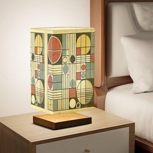 May include: A geometric patterned lamp with a wooden base. The lampshade features a design of circles, squares, and lines in shades of yellow, red, blue, and black.