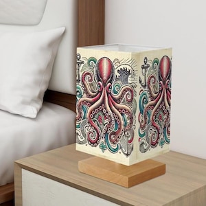 May include: A table lamp with a square shade featuring a colorful illustration of an octopus with waves and anchors. The shade is made of fabric and has a wooden base.