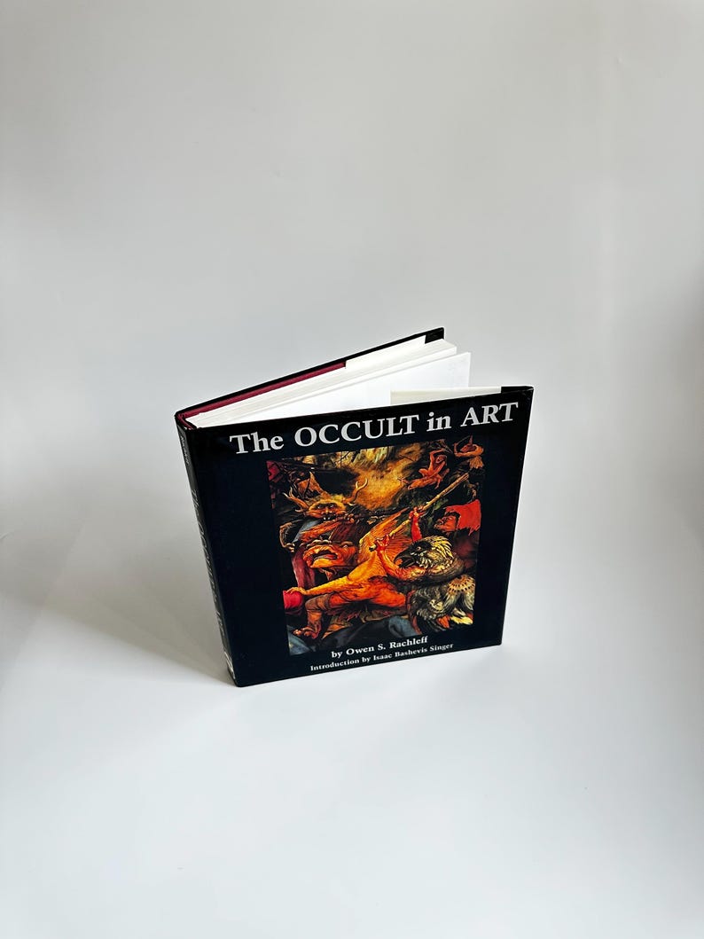 May include: A black hardcover book titled "The Occult in Art" by Owen S. Rachleff with an introduction by Isaac Bashevis Singer. The cover features a colorful illustration of a scene from a painting.
