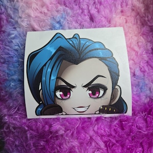May include: A sticker featuring a cartoon character with blue hair, a mischievous expression, and bright pink eyes. The character is wearing a black and gold outfit and has a white background.