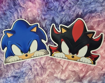 May include: Two cartoon character stickers, Sonic the Hedgehog and Shadow the Hedgehog, peeking over a surface. Sonic is blue with green eyes and Shadow is black with red highlights and red eyes.
