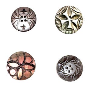 May include: Four decorative buttons with intricate designs. Two are silver-toned with star and floral patterns. One is pink and brown with a floral design, and the last is silver-toned with a spiral pattern. All have multiple holes for sewing.