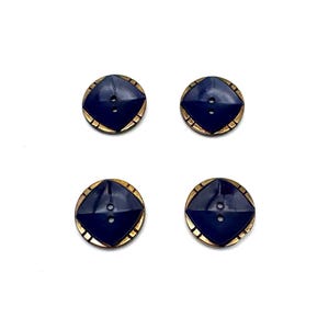 May include: Four navy blue buttons with a gold-colored border and a geometric design. Each button has two holes for sewing. The buttons are arranged in a square pattern against a white background.