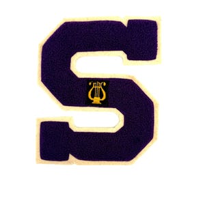 May include: A purple felt letter "S" with a cream-colored border. A gold lyre emblem is centered within the letter. This patch is likely for a varsity jacket or other apparel.