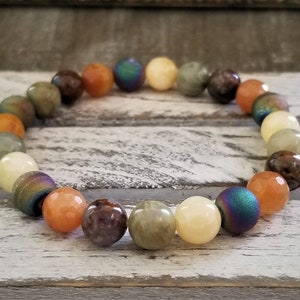 May include: A bracelet made with various semi-precious stones, including green, brown, orange, and iridescent blue beads.