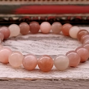 May include: A pink and white gemstone bracelet with round beads. The bracelet is made of natural stones and is approximately 7 inches in length.