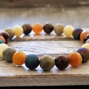 May include: A multi-colored beaded bracelet with round beads in shades of yellow, orange, brown, green, and blue.