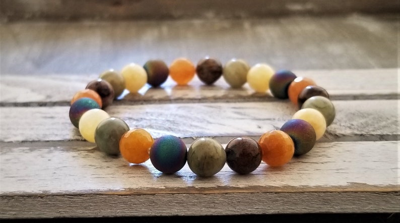 May include: A multi-colored beaded bracelet with round beads in shades of yellow, orange, brown, green, and blue.