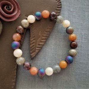 May include: A bracelet made of brown, orange, white, and iridescent beads.