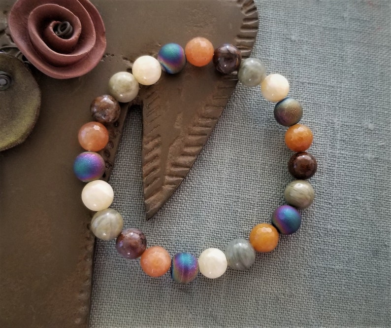 May include: A bracelet made of brown, orange, white, and iridescent beads.